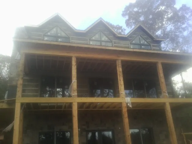Dormers and porch framing on a large log home under construction — Roof Coating work by our crew in Cheyenne