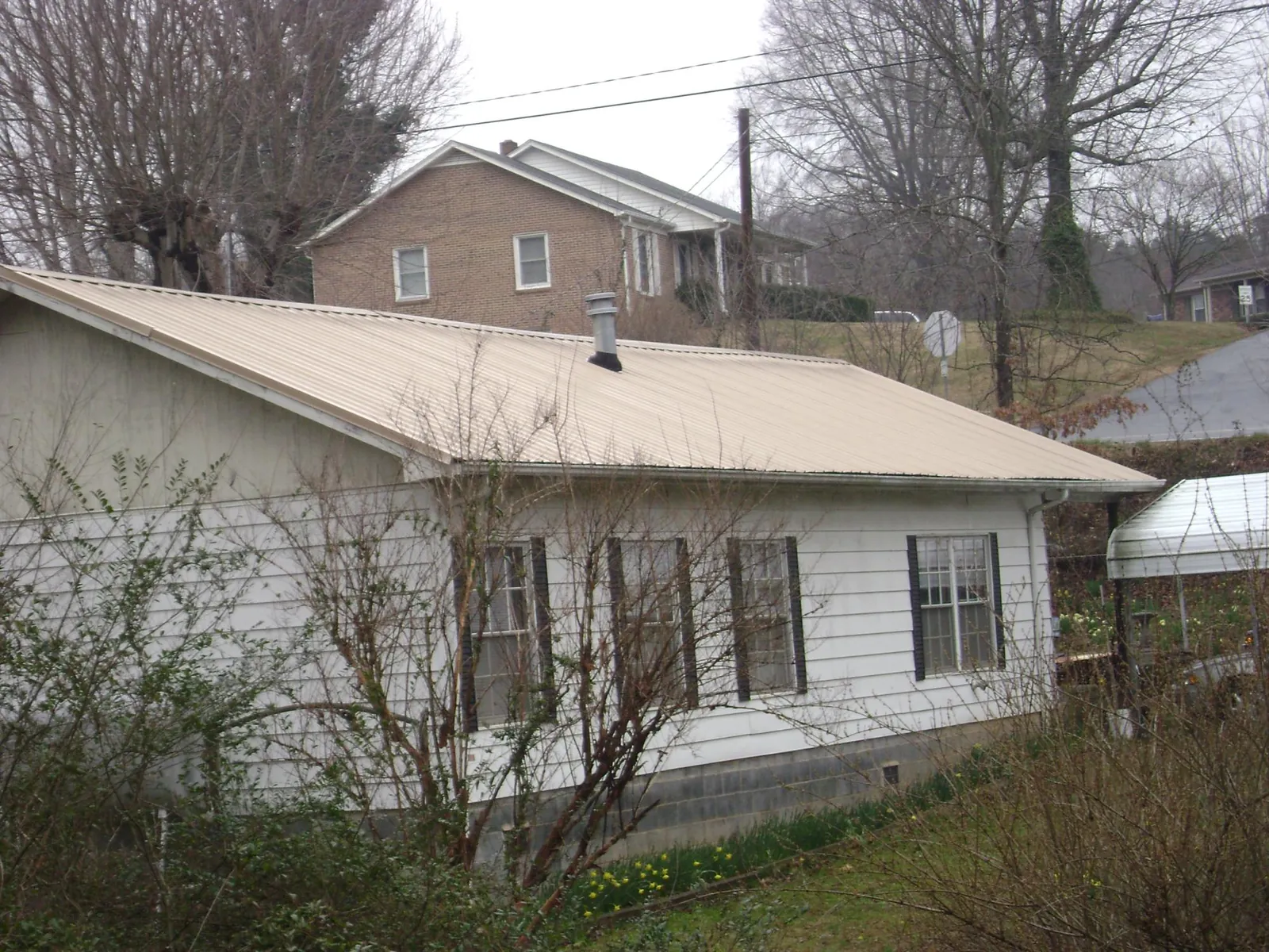 Tan metal roof on a white sided house set into a hillside — Commercial Roofing by Roofing Brothers in Cheyenne